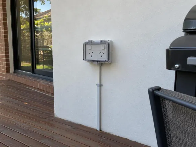 Double outdoor power point on a rendered exterior wall beside a timber deck in St Leonards